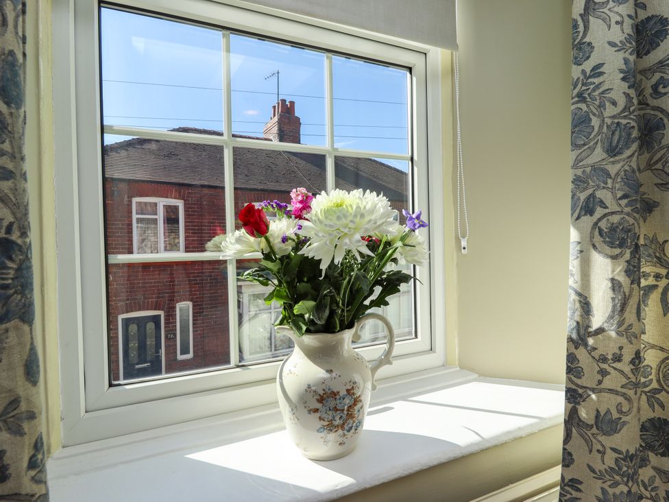 A window with a flower vase on the sill at Blue Cottage in Malton