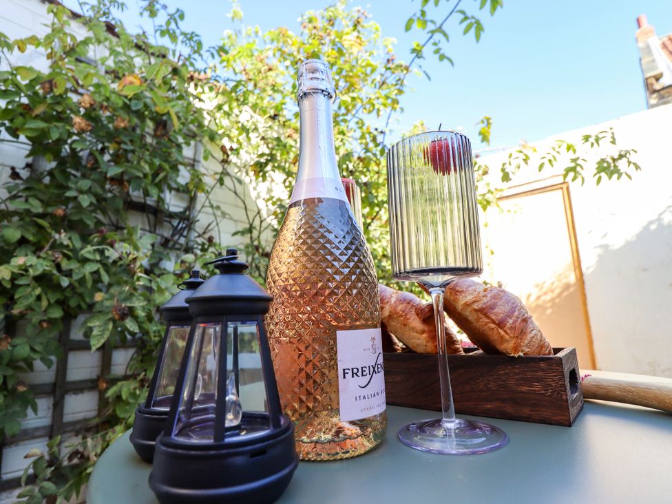 A bottle of sparkling wine, a glass, croissants, and a lantern at Blue Cottage in Malton