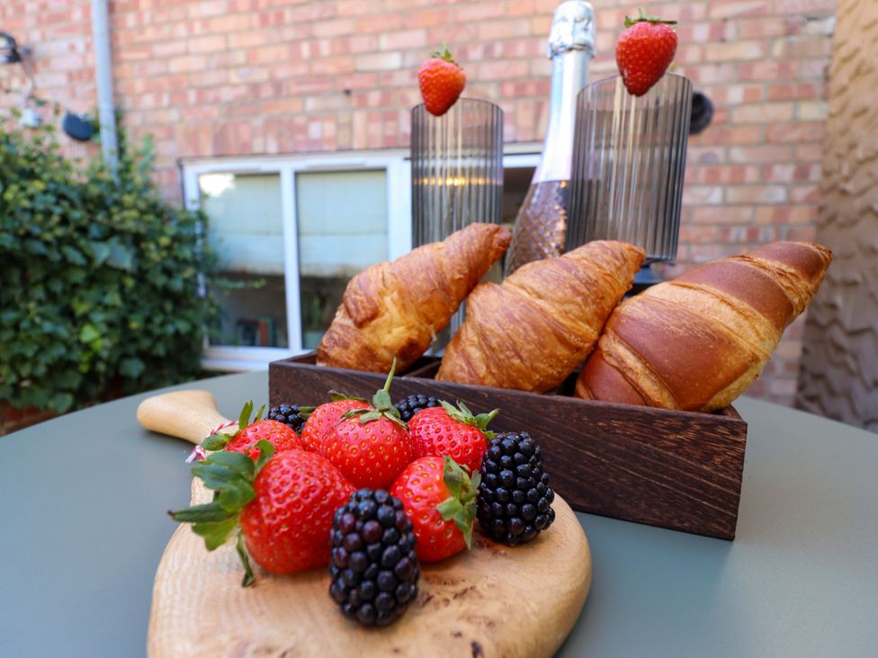 A wooden platter with strawberries and blackberries and croissants at Blue Cottage Malton