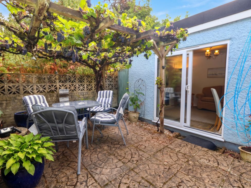 A garden with a table and chairs under a grapevine at Sunnydale near Corfe Mullen