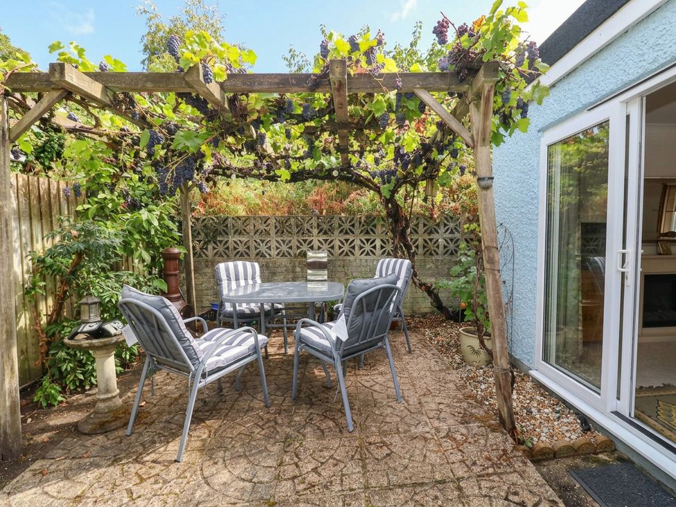 A garden with a table and chairs under a pergola at Sunnydale near Corfe Mullen