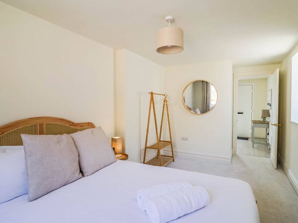 A bedroom with a bed, towels, and a mirror at 30 Southdown Avenue Weymouth