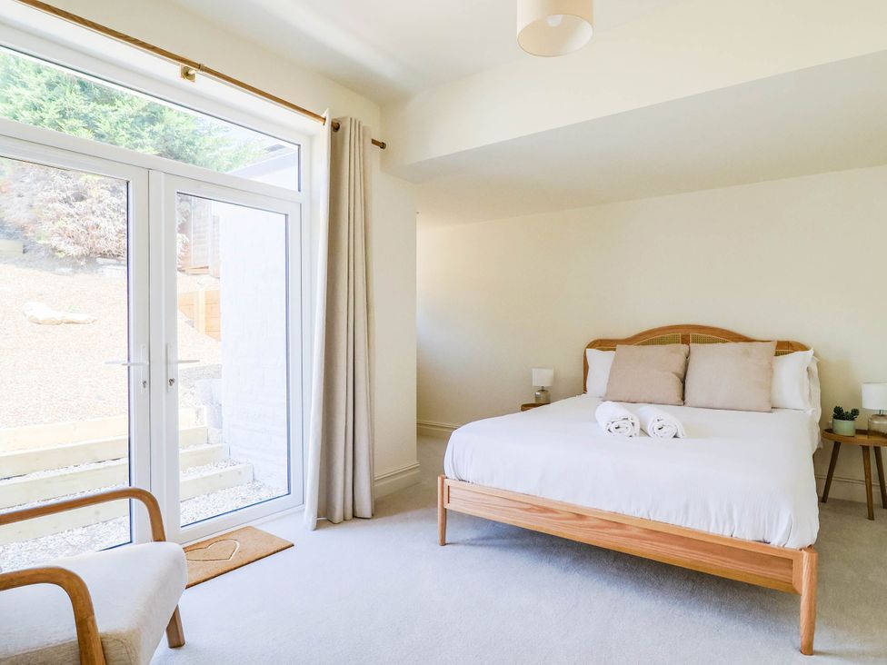 A bedroom with a bed and large windows at 30 Southdown Avenue Weymouth