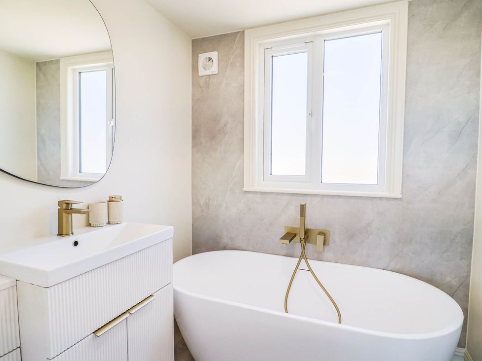 A bathroom with a bathtub, sink, and window at 30 Southdown Avenue Weymouth