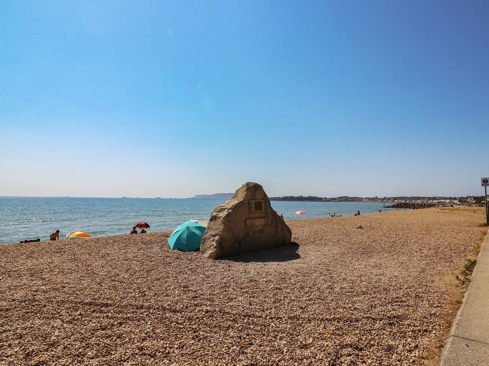 A beach with pebbles and umbrellas near the sea at 30 Southdown Avenue Weymouth