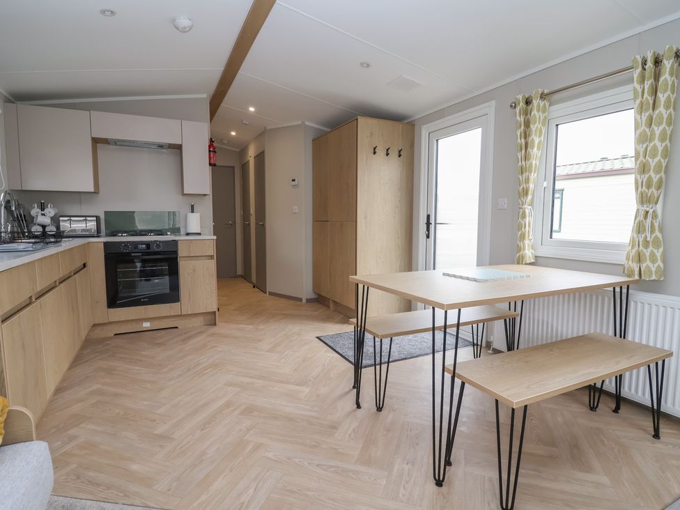 A kitchen with cabinets and a dining table at S7 Abergele