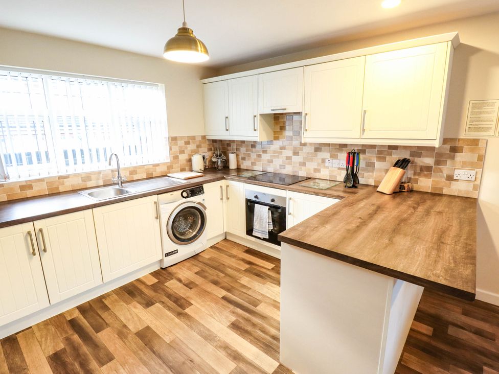 A kitchen with a sink, washing machine, and oven at Beach Lodge