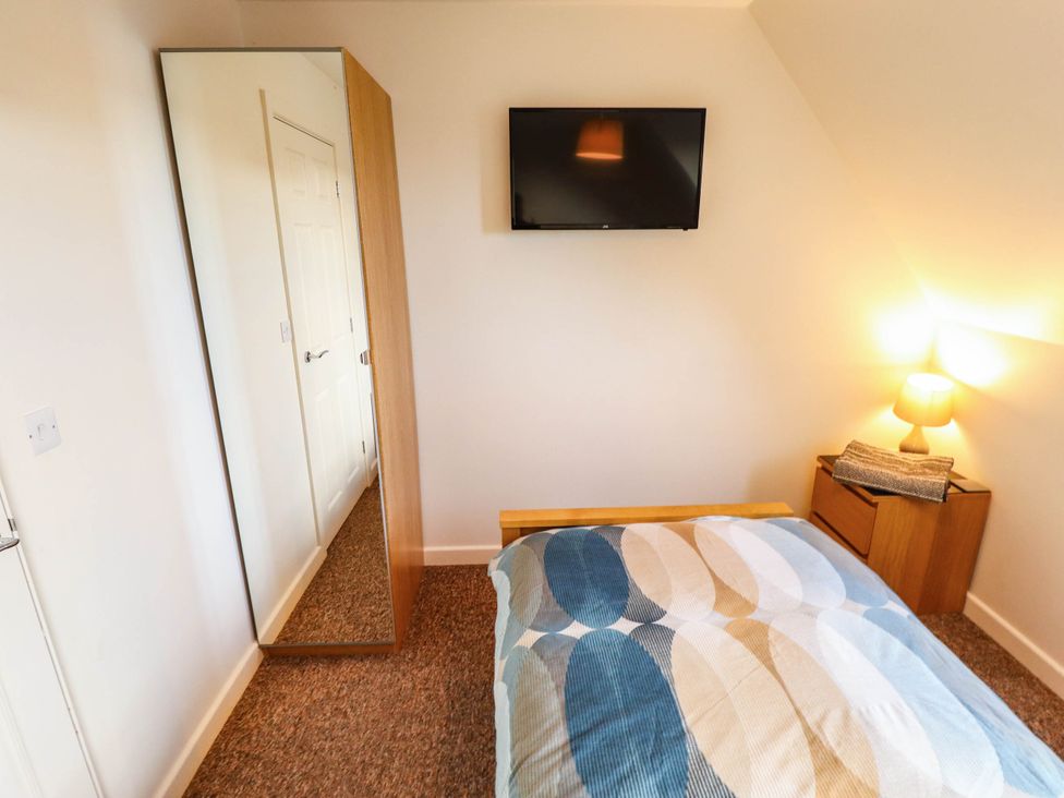 A bedroom with a bed, mirror, and television at Beach Lodge