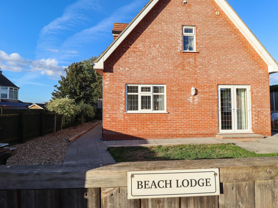A house with a patio and grass area at Beach Lodge