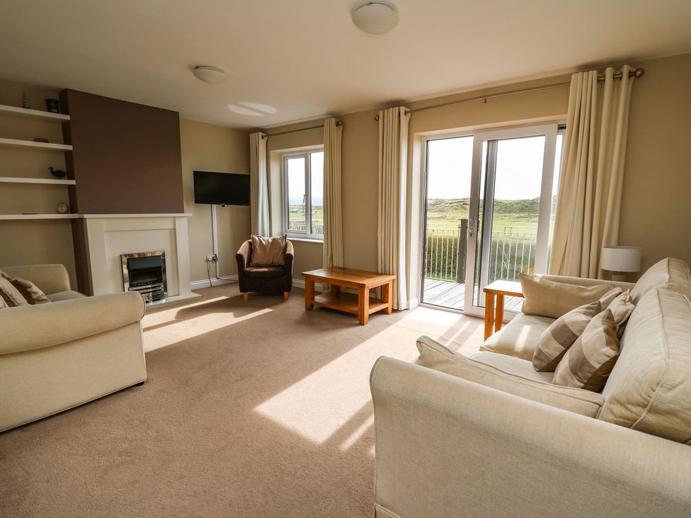 A living room with a sofa, coffee table, and armchair at Ty'r Heulwen Aberdovey
