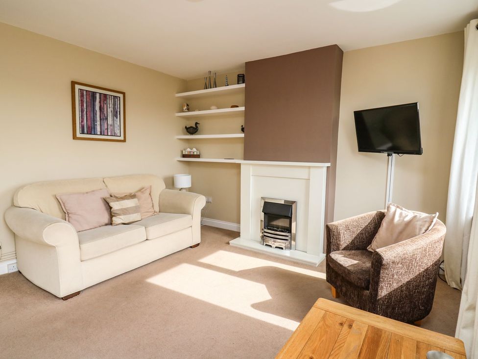 A living room with a sofa and television at Ty'r Heulwen in Aberdovey