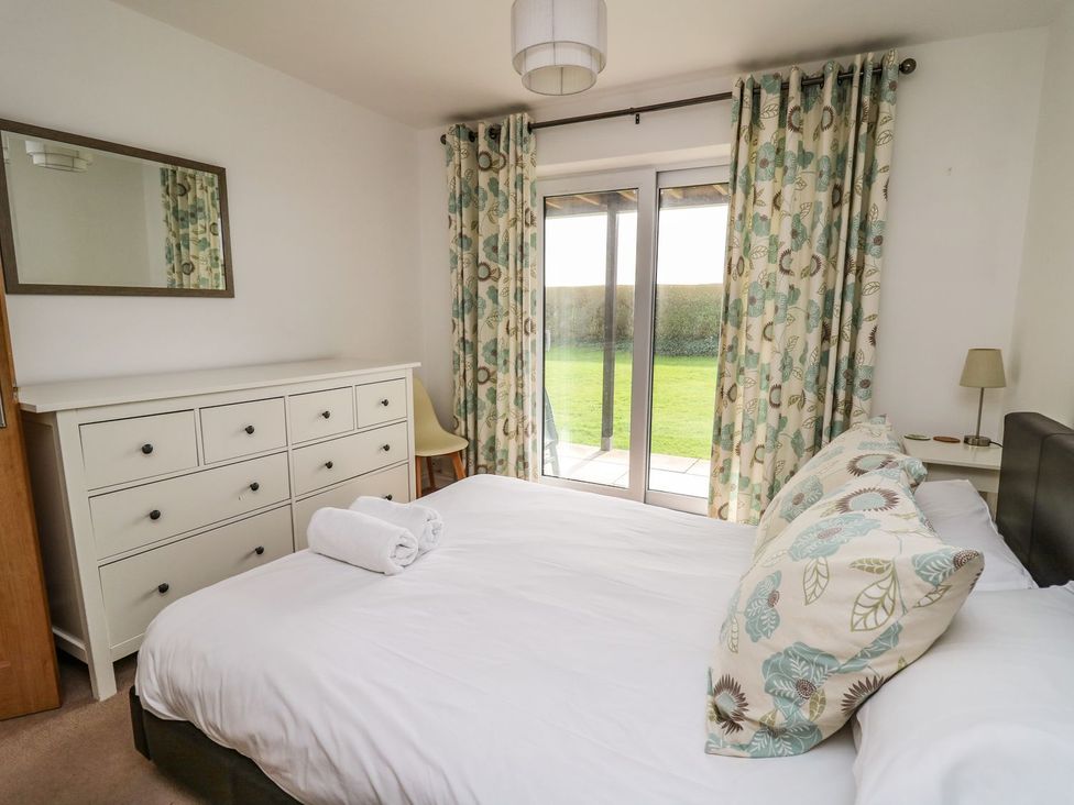 A bedroom with a bed and a chest of drawers at Ty'r Heulwen Aberdovey