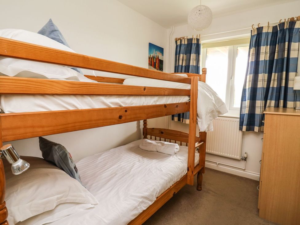 A bedroom with a bunk bed and chest of drawers at Ty'r Heulwen in Aberdovey