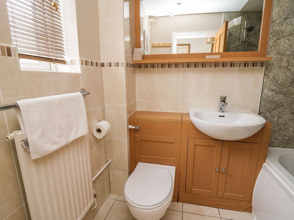 A bathroom with a sink, toilet, and storage cabinet at Ty'r Heulwen Aberdovey