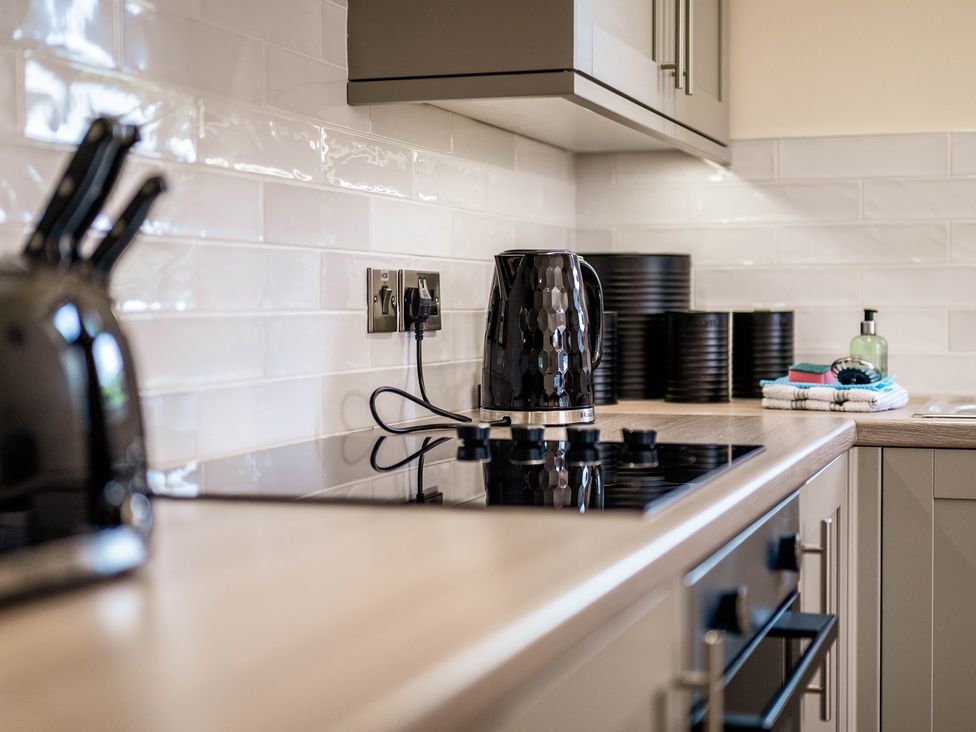 A kitchen countertop with a kettle and cooking hob at Bay Bungalow