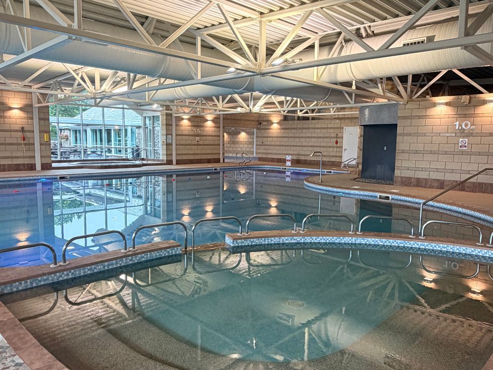 An indoor pool with a ladder and windows at Bay Bungalow near Carnforth