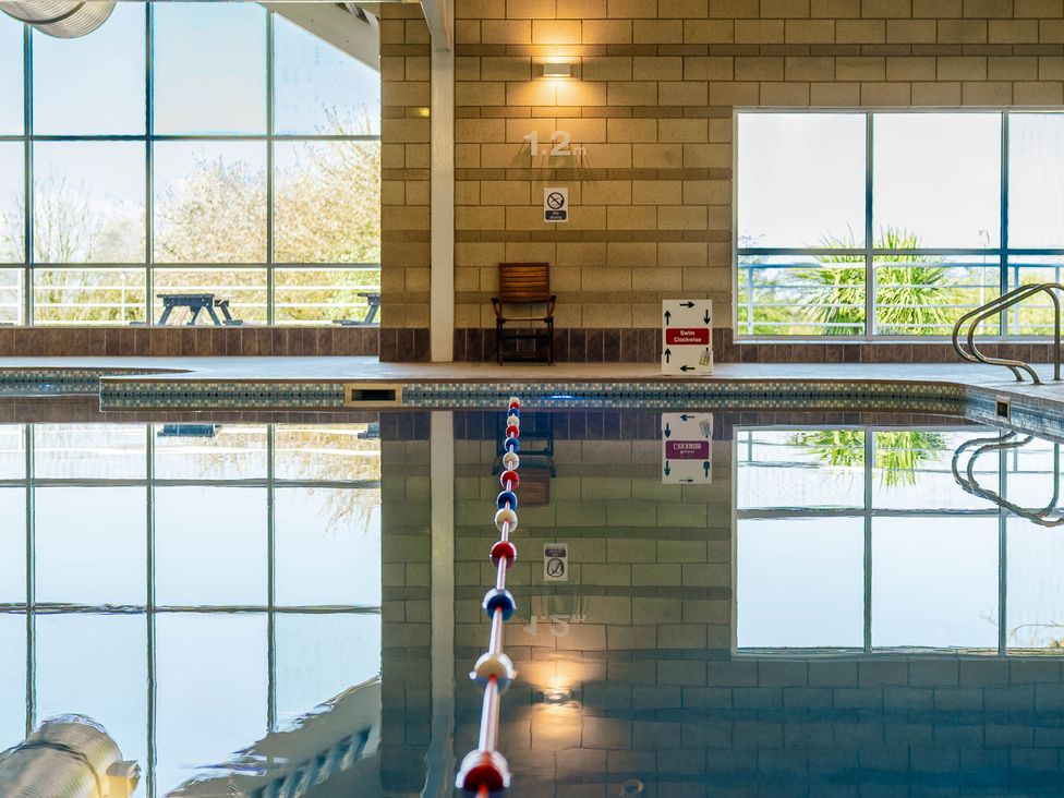 An indoor swimming pool with a lane divider and seating at Bay Bungalow near Carnforth