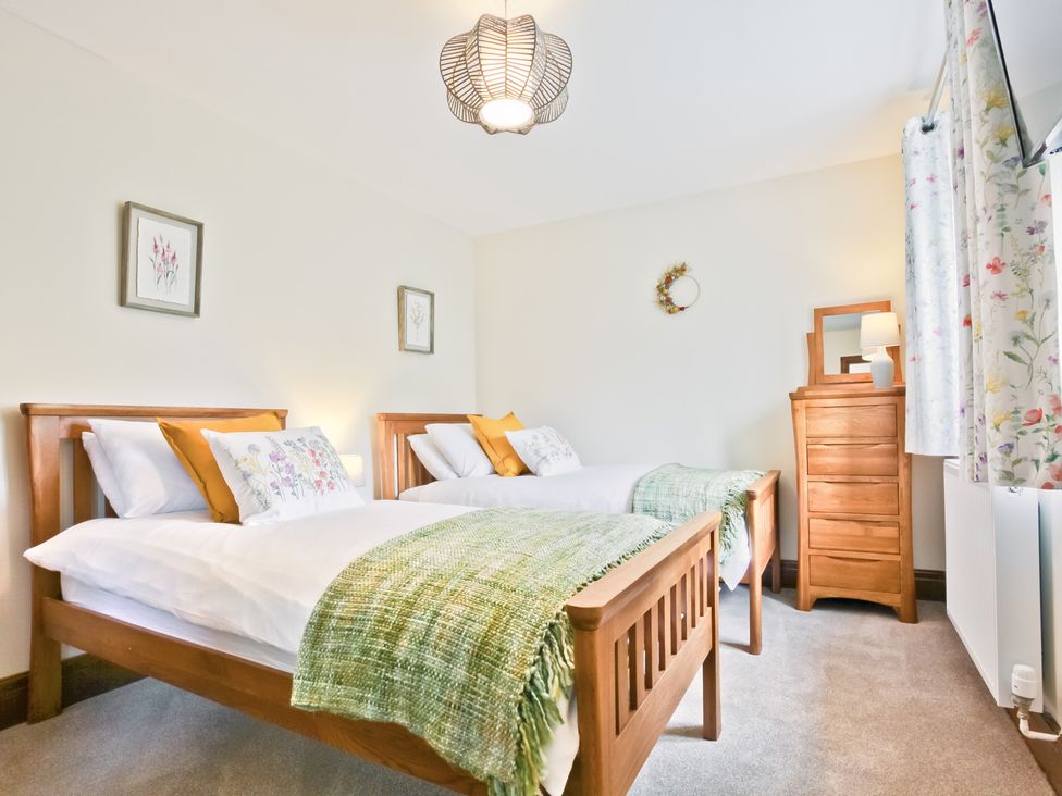 A bedroom with two beds and a dresser at Hillberry Cottage in Carnforth