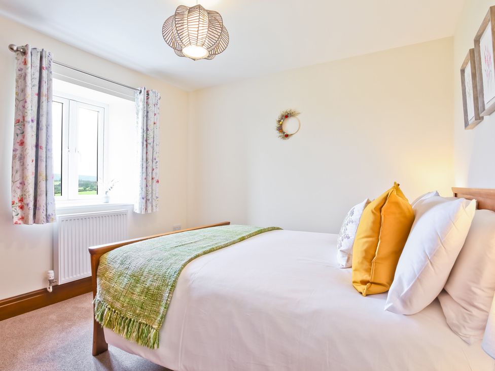 A bedroom with a bed and windows at Hillberry Cottage in Carnforth