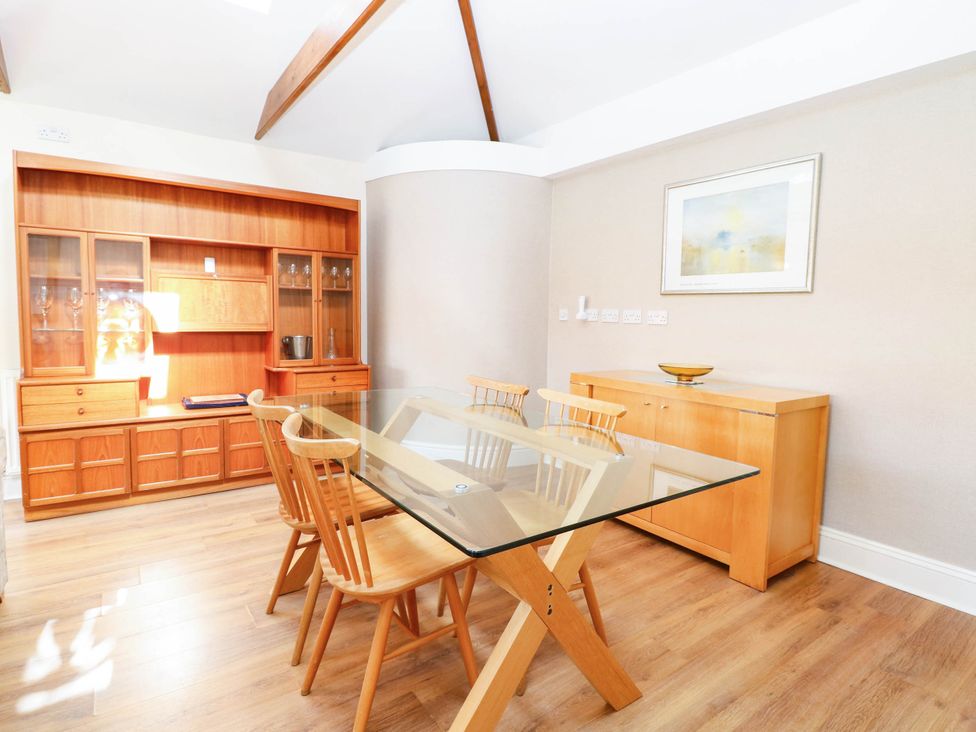 A dining room with a glass table and wooden chairs at The Mill House Apartment in 