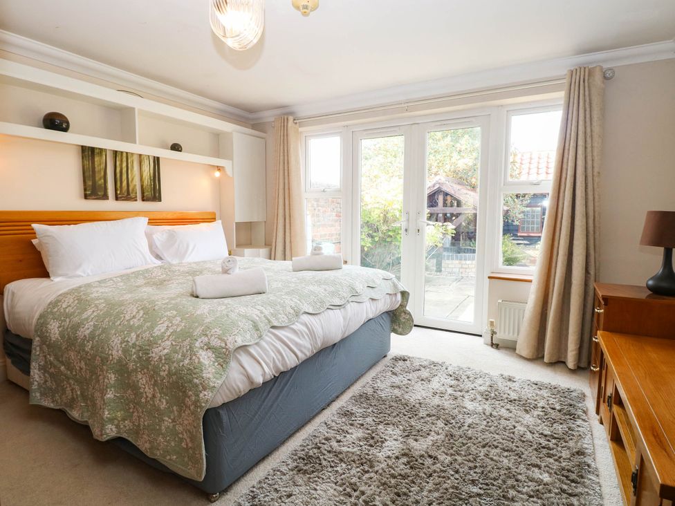 A bedroom with a bed and double doors leading to the outside at The Mill House Apartment