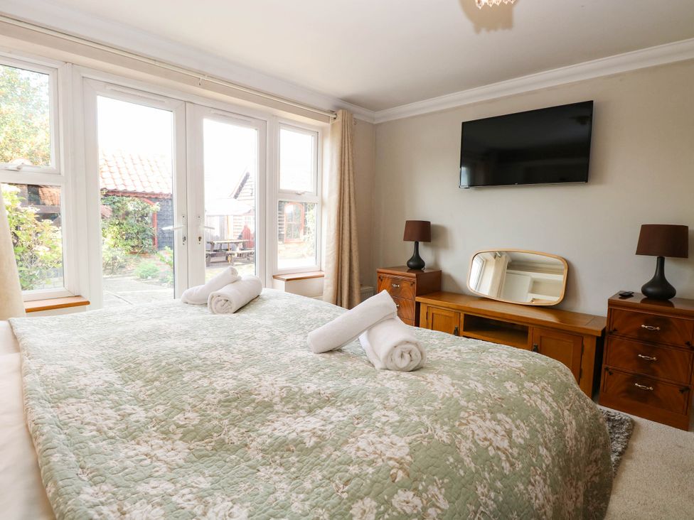A bedroom with a bed and television at The Mill House Apartment