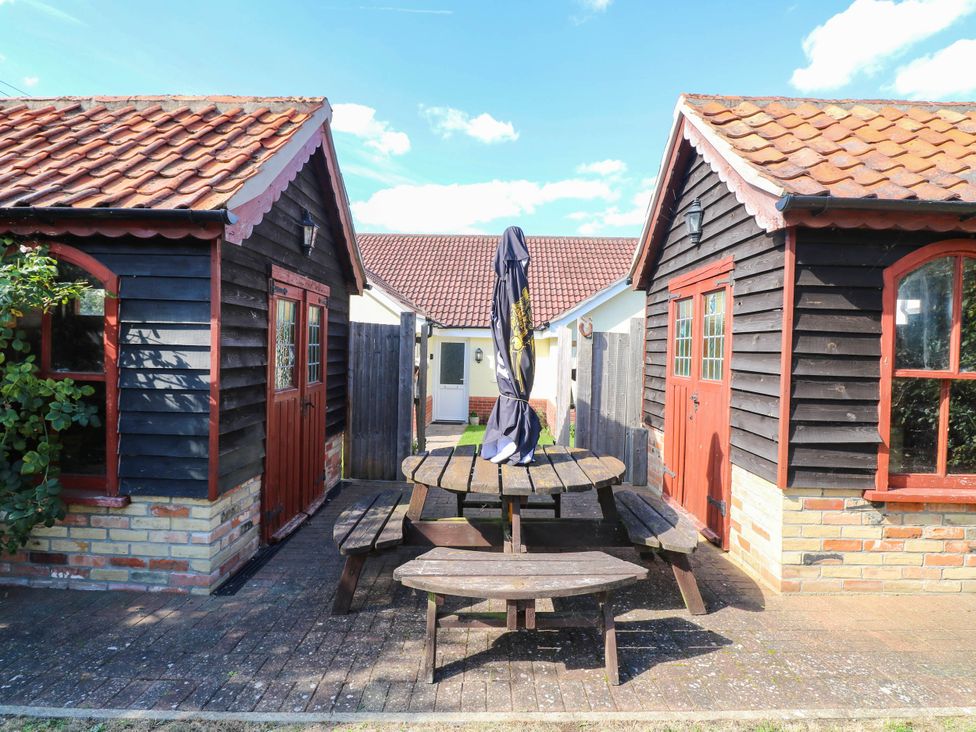 A picnic table with chairs and umbrella between two wooden buildings at The Mill House Apartment