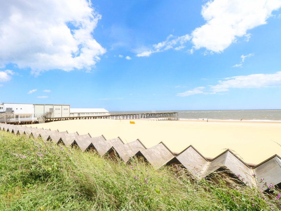 A beach with a pier and grass at The Mill House Apartment in 