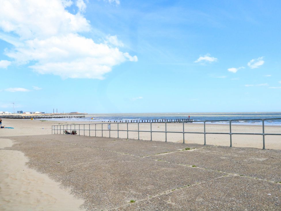 A beach scene with a railing and a pier at The Mill House Apartment