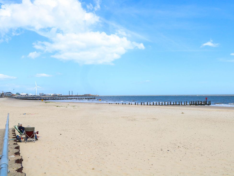A view of a beach with a pier and wind turbine at The Mill House Apartment in 