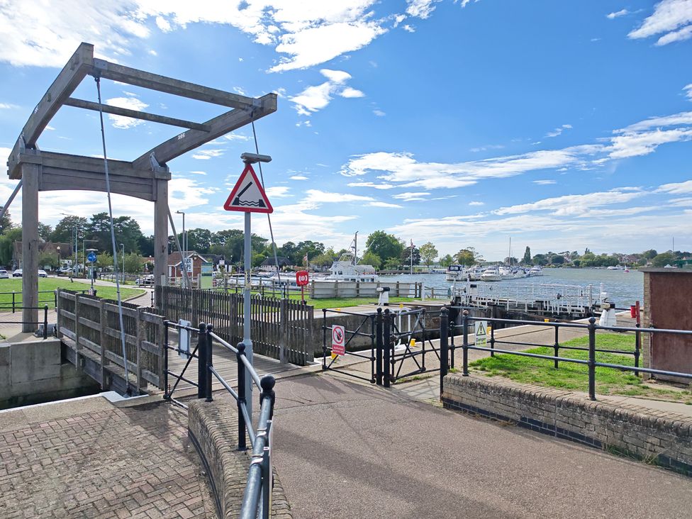 A wooden bridge over water with boats visible at The Mill House Apartment Oulton Broad
