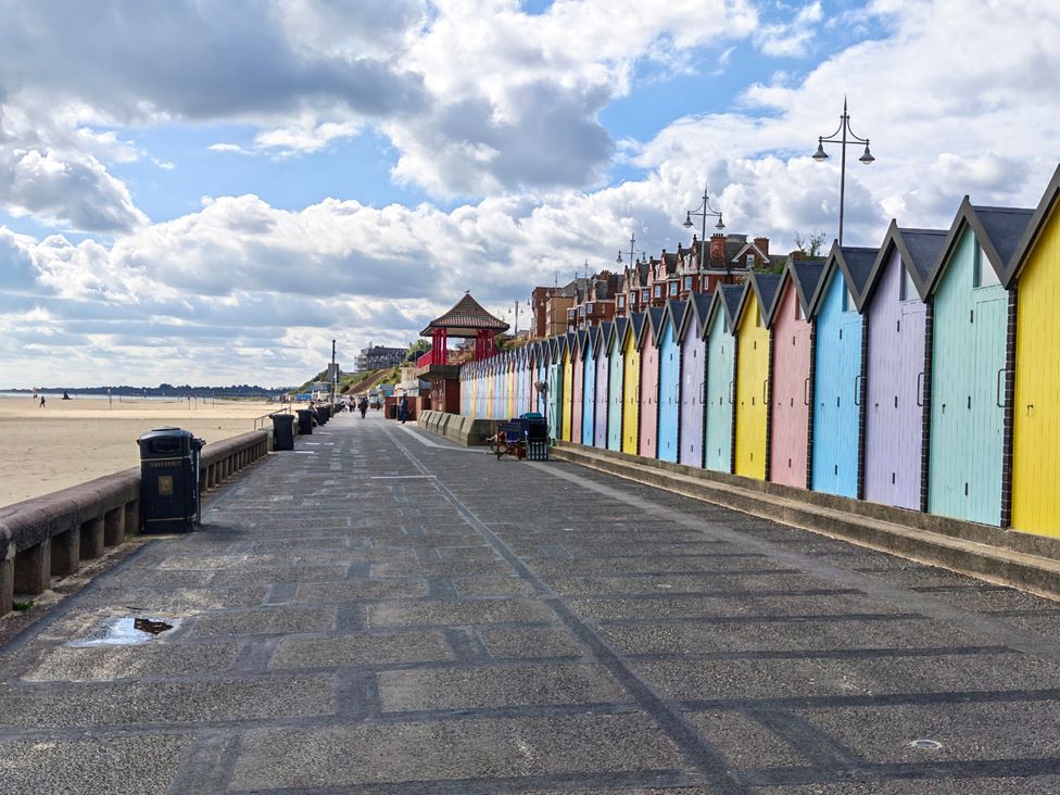 An outdoor area with colorful beach huts and a walkway by the beach at The Mill House Apartment Oulton Broad