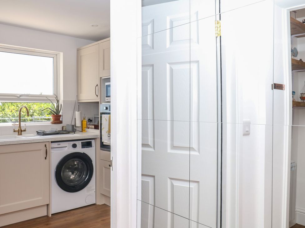 A laundry room with a washing machine and kitchen sink at Elberry Cove View Paignton