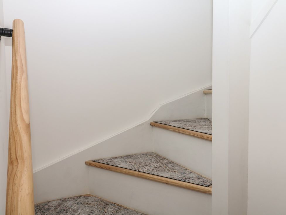 A staircase with wooden handrail at Elberry Cove View in Paignton