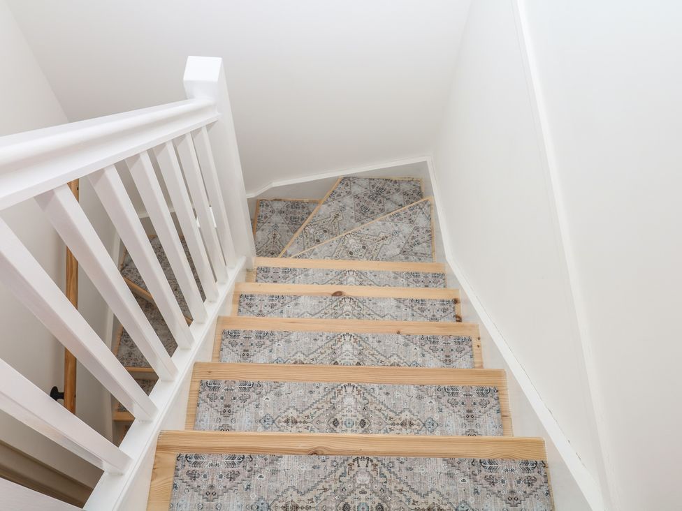 A staircase with a carpet runner at Elberry Cove View in Paignton
