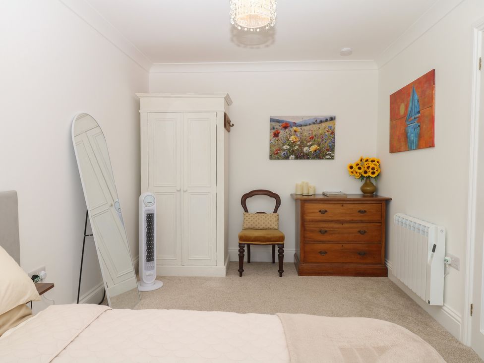 A bedroom with a bed, wardrobe, chair, and table at Elberry Cove View in Paignton