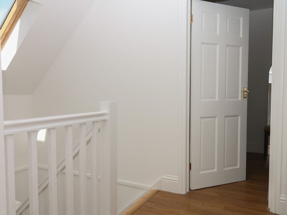 A hallway with a railing and an open door at Elberry Cove View in Paignton