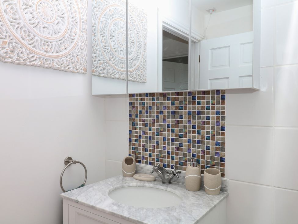 A bathroom with a sink and decorative tiles at Elberry Cove View in Paignton