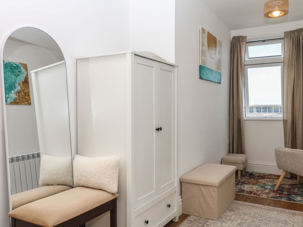A bedroom with a wardrobe and a mirror at Elberry Cove View in Paignton