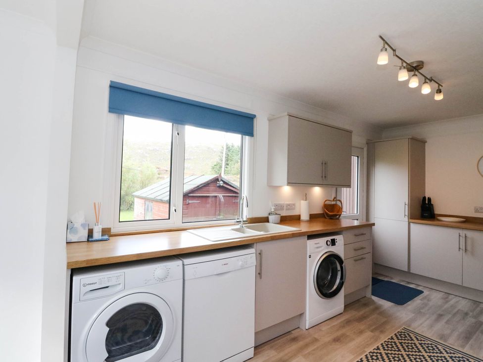 A kitchen with a washing machine, dishwasher, and sink at Skye View, Isle of Harris