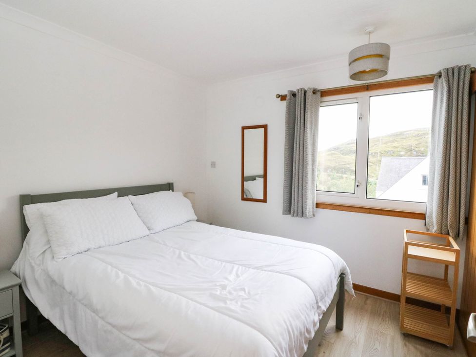 A bedroom with a bed, a mirror, and a window at Skye View, Isle of Harris