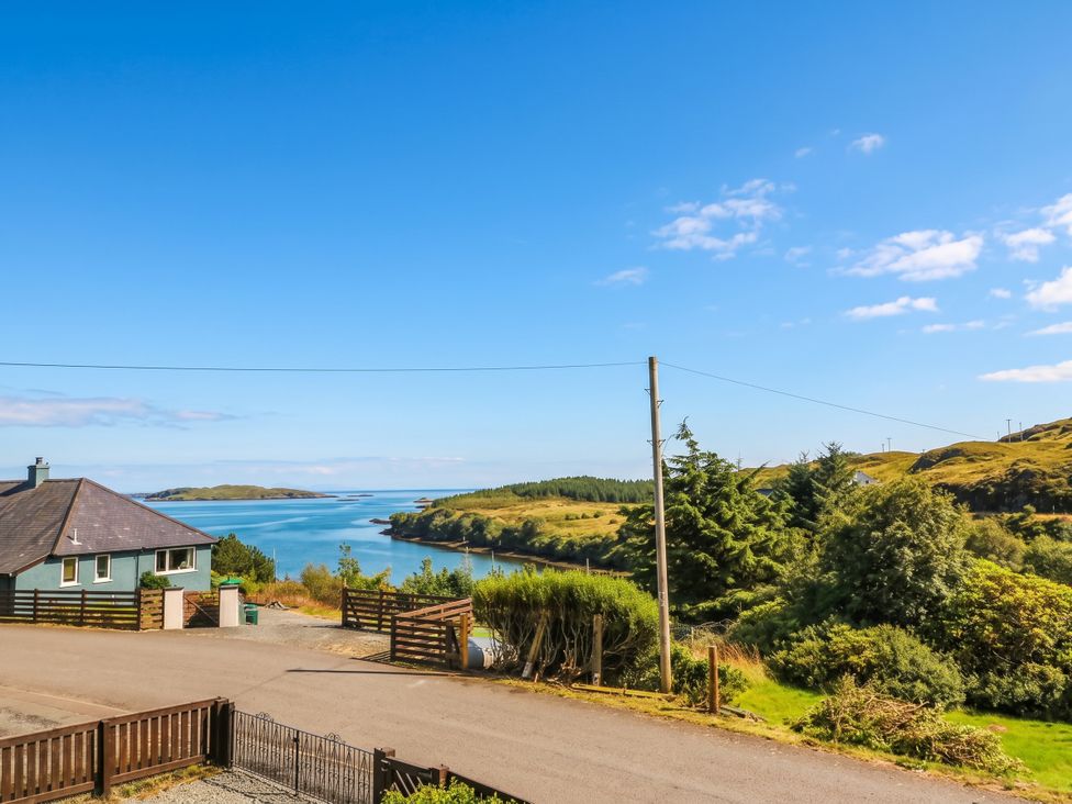 A house and road overlooking water and hills at Skye View in Isle of Harris