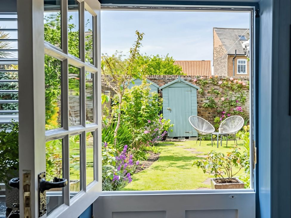 A view of a garden with a storage shed and seating area at CobNut Cottage in Sandwich