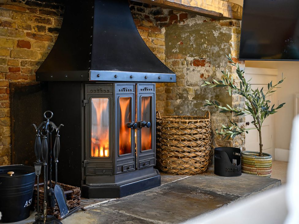 A fireplace with a stove in a living room at CobNut Cottage in Sandwich