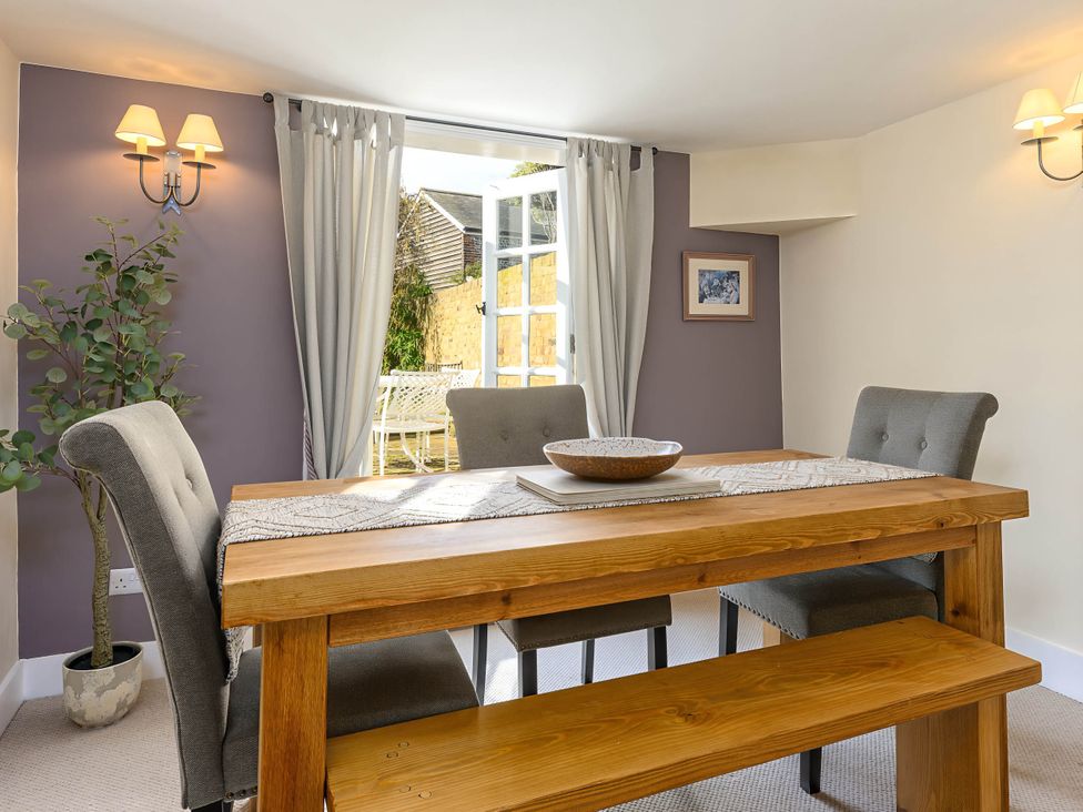 A dining room with a wooden table and grey chairs at CobNut Cottage Sandwich