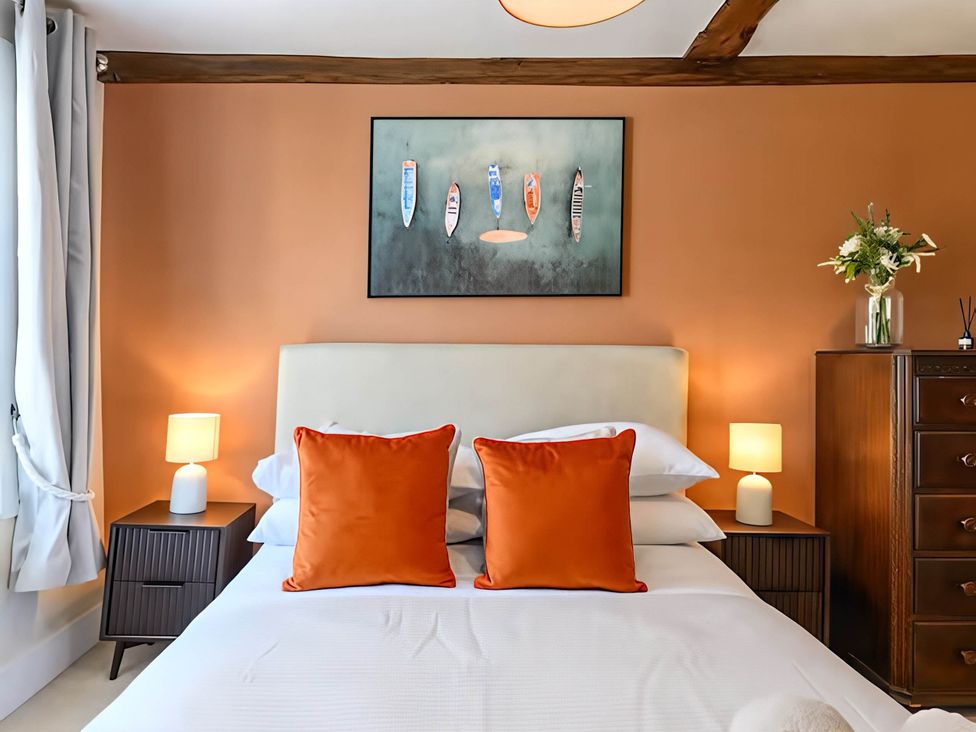 A bedroom with a bed and orange pillows at CobNut Cottage in Sandwich