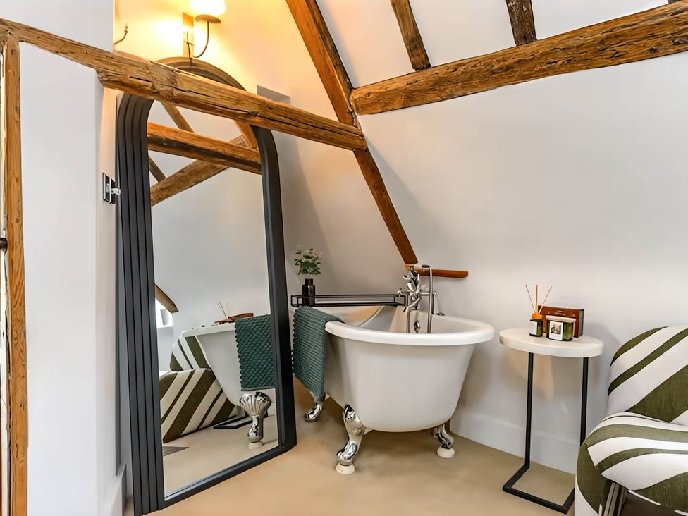 A bathroom with a bathtub and mirror at CobNut Cottage in Sandwich