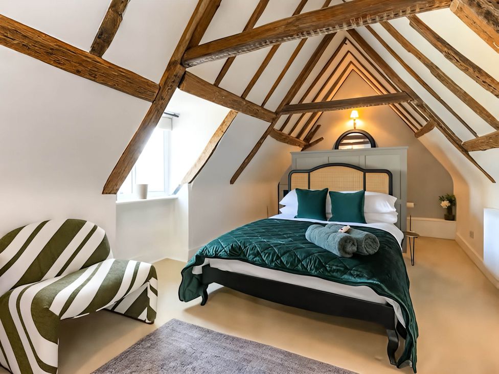 A bedroom with a bed and a chair at CobNut Cottage in Sandwich