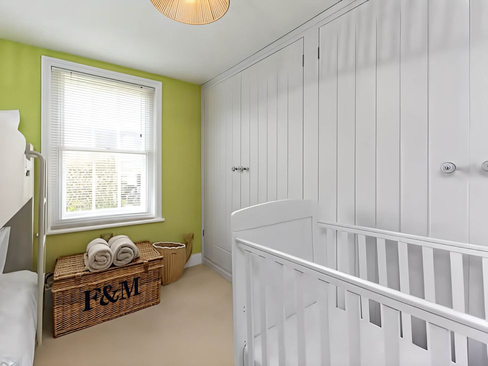A nursery with a crib and storage basket at CobNut Cottage Sandwich