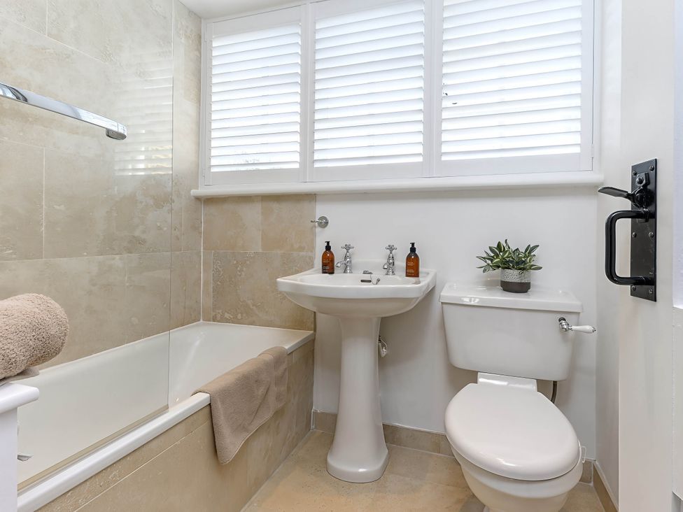 A bathroom with a bathtub, washbasin, and toilet at CobNut Cottage Sandwich